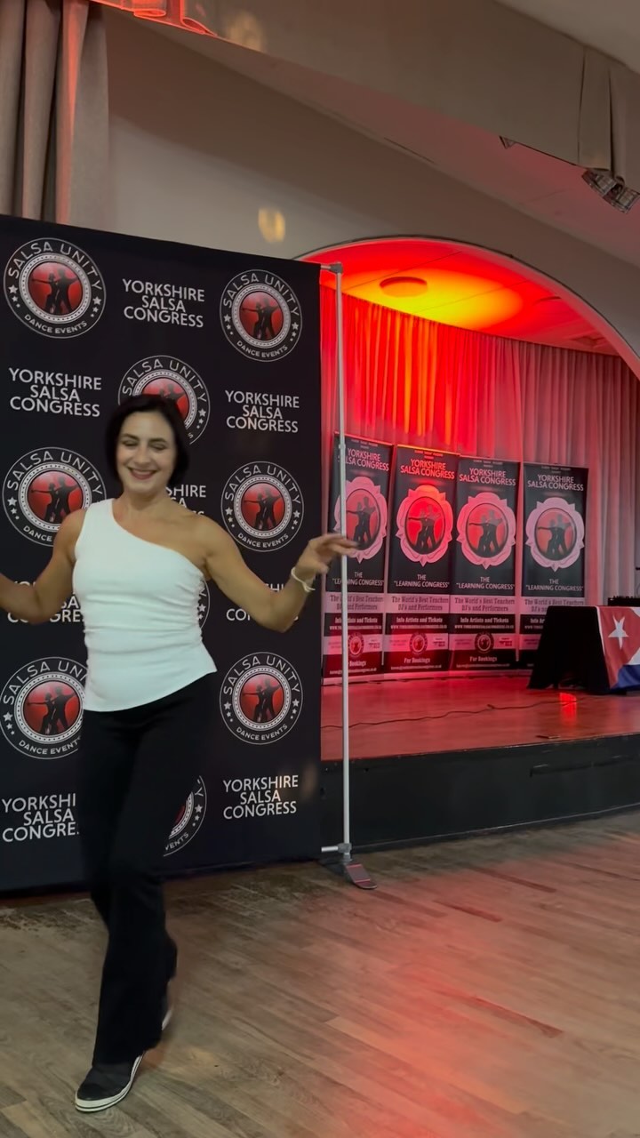 Karen Salsa McQuire dancing in front of the Salsa Unity banner